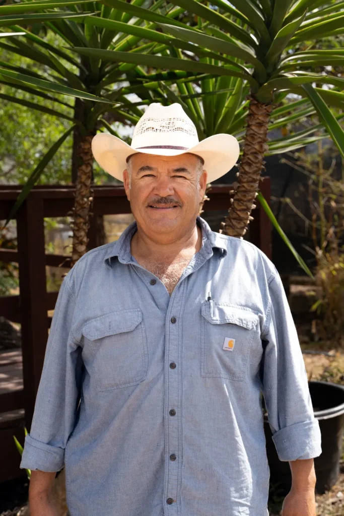 Saúl Padilla standing outdoors in a cowboy hat and blue Carhartt shirt